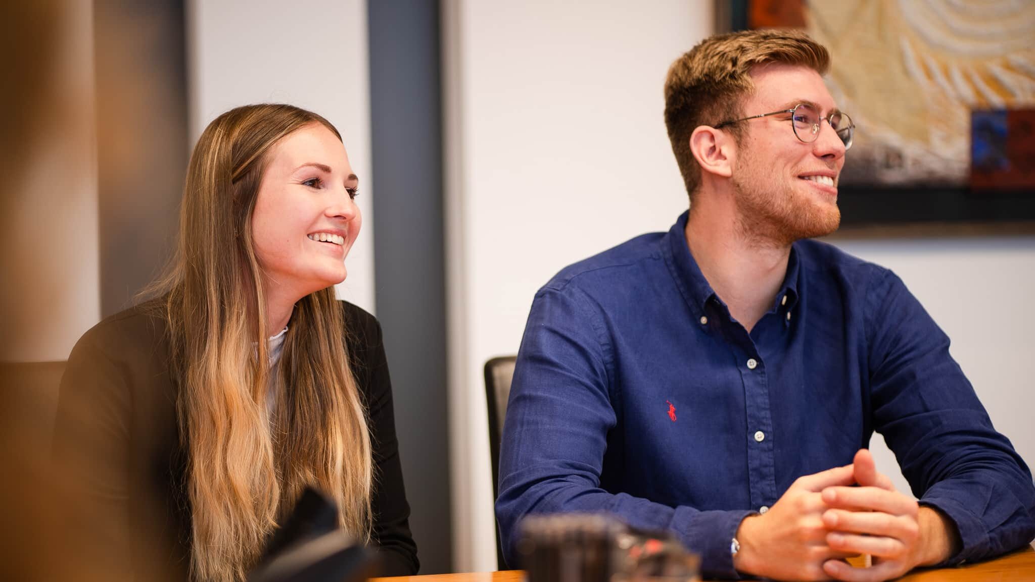 Frau und Mann im Teammeeting lachend